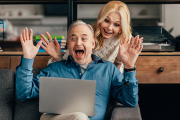 excited couple looking at laptop while having video call