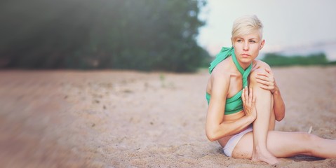 Summer lifestyle portrait of pretty young girl with tanned sexy body. Doing yoga stretching exercise and sitting at the tropical island beach Wearing stylish bikini Young healthy woman practicing yoga
