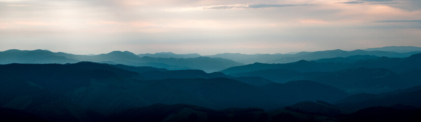 Fototapeta premium Background panorama with mountains in the fog. Dark sunset time