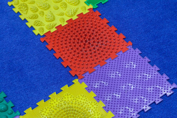 Children's large mosaic multi colored constructor on a blue carpet background. Baby mat massager