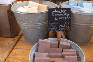 Bars of colourful home made soap in large metal pails for sale at a Farmers Market