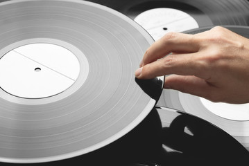 Vinyl record in male hand. Several vinyl records in the background