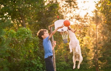 Kid playing basketball with his dog in backyard garden © alexei_tm