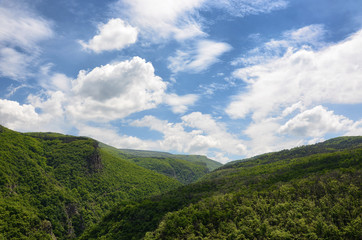 Spring mountain landscape with white puffy clouds 