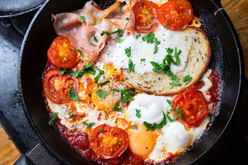 Fried eggs with bacon, toast and tomatoes in a pan