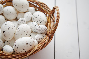Naklejka na ściany i meble Basket of white dotted Easter eggs in brown wicker basket