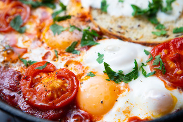 Fried eggs with bacon, toast and tomatoes in a pan