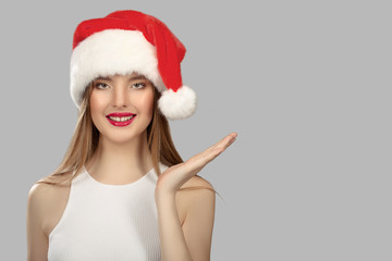 Portrait of an attractive cute woman wearing a santa hat. Gray, blue background