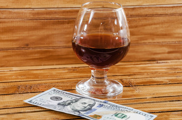 dollars and a glass of wine on a wooden background