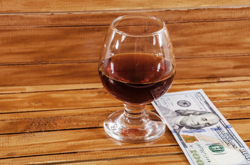 dollars and a glass of wine on a wooden background