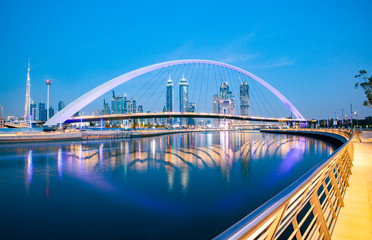 Naklejka premium kolorowy zachód słońca nad drapaczami chmur w centrum Dubaju i nowo wybudowanym mostem Tolerance, patrząc z kanału wodnego w Dubaju