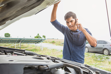 Stressed man having trouble with his broken car looking in frustration at failed engine.Driver on...