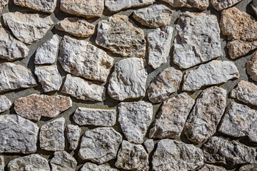Wall made of cement and irregularly shaped stones. Architectural detail, closeup. Texture, material background.