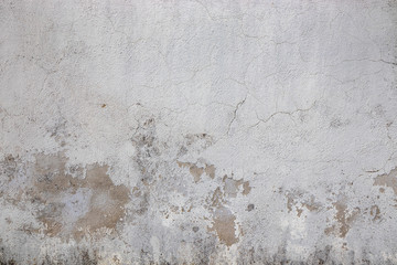 Gray wall ruined by time, bad weather and humidity. Cracks, mold, peeling paint and plaster. Texture, material background.