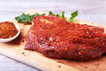 Raw beef steak with spices Leaves of coriander on wooden cutting board. Ready for cooking.