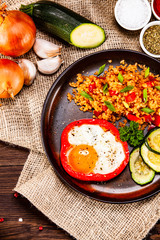 Fried egg, groats and vegetables on wooden table