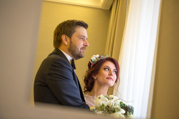 Cheerful wedding couple posing in hotel room