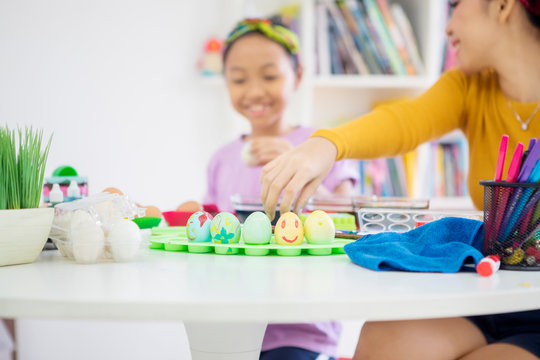 Child decorating Easter eggs with her mother