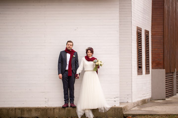 Beautiful wedding couple with neckclouds posing in front of white house