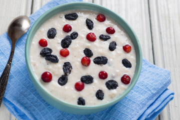 oatmeal with raisins and cranberries on a wooden table. wholesome breakfast