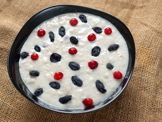 oatmeal with raisins and cranberries on a wooden table. wholesome breakfast