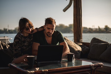 Serious couple working on laptop by the river