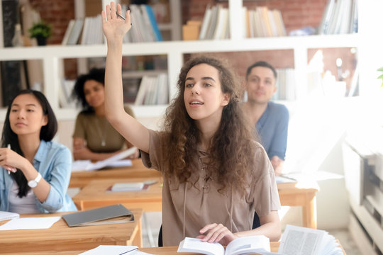 Teen female college university student raising hand during class