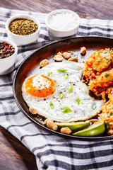 Grilled chicken meat with groats and fried egg on wooden table