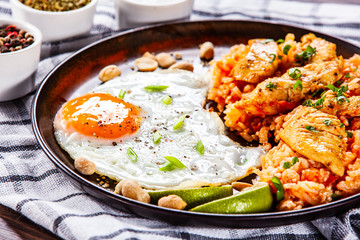 Grilled chicken meat with groats and fried egg on wooden table