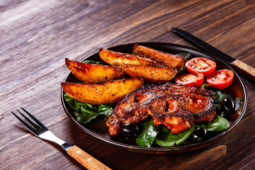 Grilled steak with potatoes and vegetables on wooden table