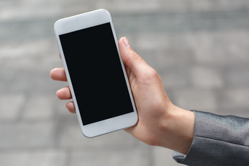 Business woman standing on the city street showing smartphone screen close-up