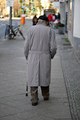 An old man walks along a street in Berlin-Germany on a cold day.