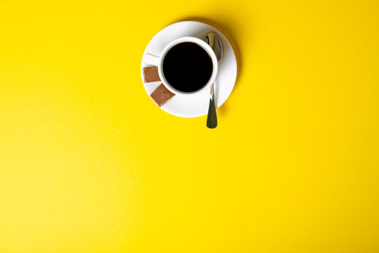 Cup of coffee with chocolate pieces on yellow background, top view © Kabardins photo