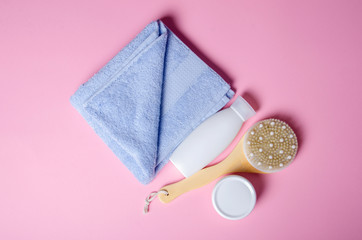 White towel, jar cream, lotion, massage brush soft beauty on pink background, top view