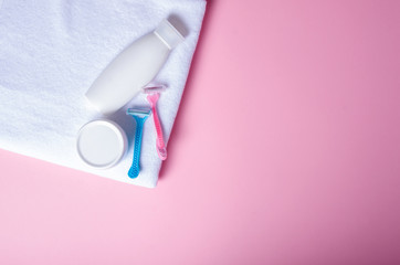 White towel, jar cream, lotion, razor, roller deodorant soft beauty on pink background, top view