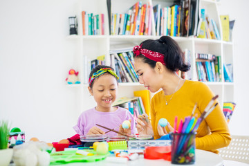 Fototapeta premium Mother teaches her daughter to paint Easter eggs