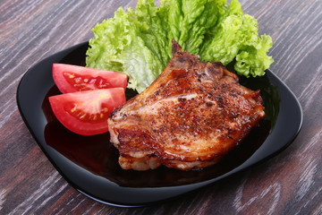 grilled pork chops with tomato, leaves lettuce and ketchup on plate.
