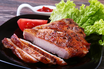 grilled pork chops with tomato, leaves lettuce and ketchup on plate.