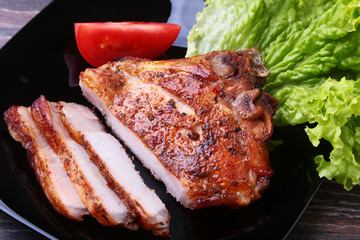 grilled pork chops with tomato, leaves lettuce and ketchup on plate.