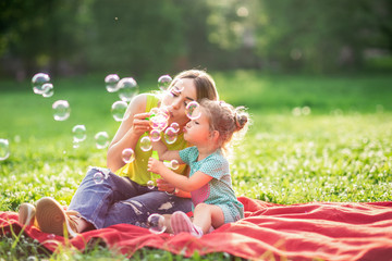 Happy Childhood – Young Mother and child blows soup foam and make bubbles .