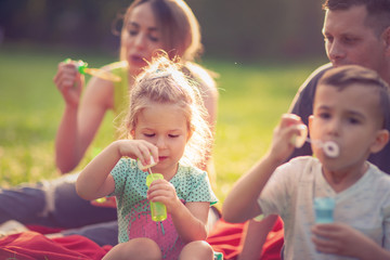 girl blows soap bubbles with her family in the park.