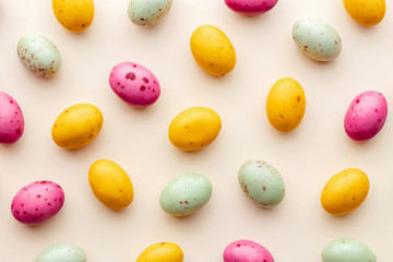 Easter chocolate eggs candy on a pastel yellow background, creative flat lay easter concept, top view