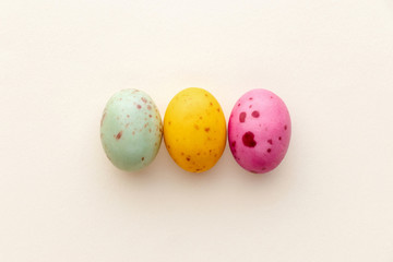 Easter chocolate eggs candy on a pastel yellow background, creative flat lay easter concept, top view