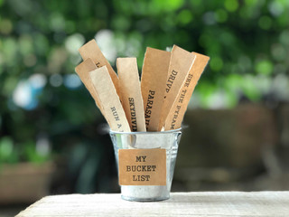 Motivational and inspirational concept - My Bucket List written on paper. There are list of wishes written on papers and placed inside the bucket. Blurred vintage styled background. © Coompia77