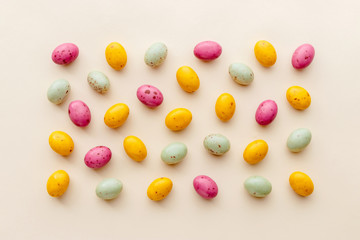 Easter chocolate eggs candy on a pastel yellow background, creative flat lay easter concept, top view
