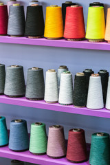different color spools of thread for the textile industry on the shelf