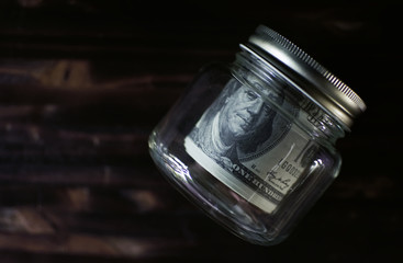Banknote in the glass jar on old brown wood, saving concept. color of retro style.