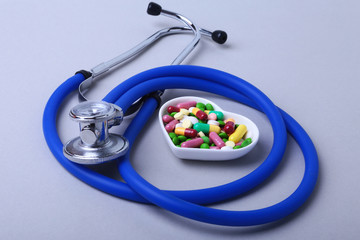 Stethoscope, RX prescription and colorful assortment pills and capsules on plate.