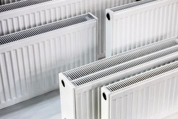 many metal radiators of different sizes. background of heating batteries