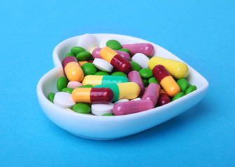 colorful assortment pills and capsules on plate.